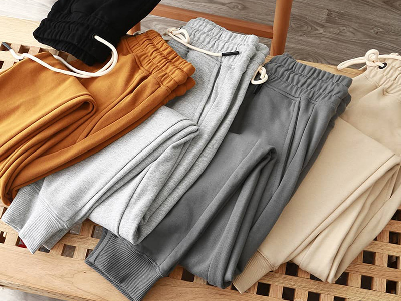 Folded jogger sweatpants in black, mustard, light gray, dark gray, and cream tones.