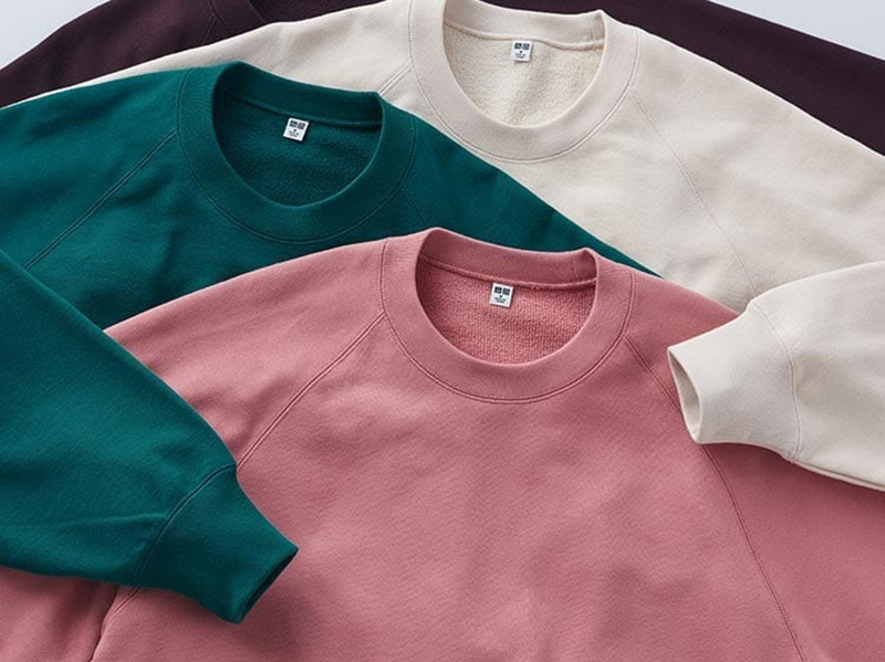 Four crewneck sweatshirts layered in burgundy, cream, teal, and pink tones.