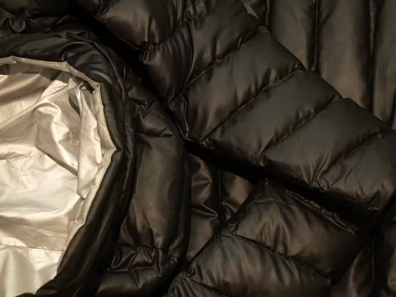 Close-up of black quilted puffer jacket with insulated glossy fabric texture