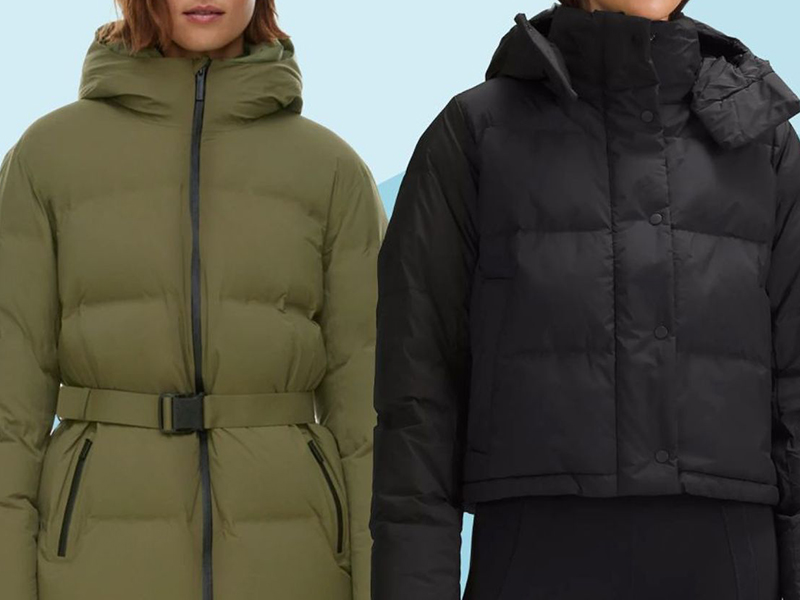 Two women wearing puffer jackets: one in olive green with a belt and zip closure, the other in black with a high collar, hood, and snap button closure. Only the torsos and part of the faces are visible.