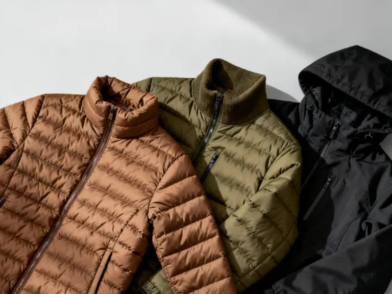 Three quilted jackets laid side by side, in warm brown, olive green, and black, with zippers and different collar styles, displayed on a light background.