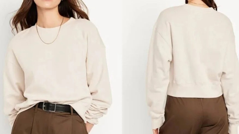Woman wearing a cream cropped sweatshirt shown from front and back with relaxed fit.