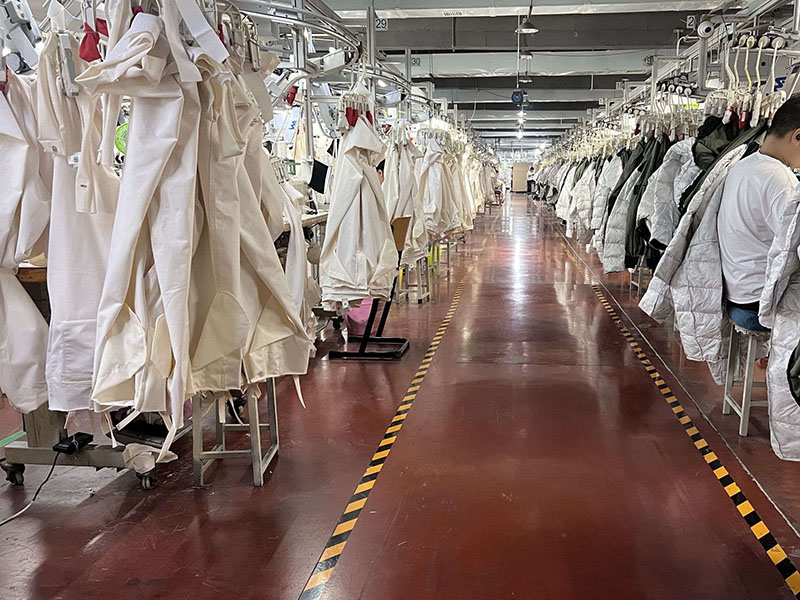 Large garment factory with hanging jackets and clothing production assembly lines