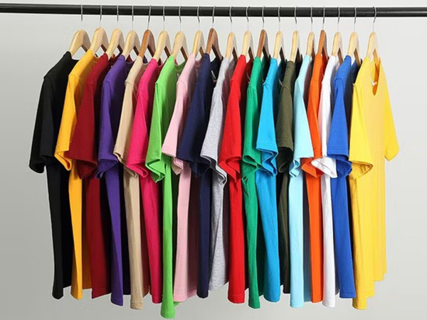 Assorted colorful cotton T-shirts hanging neatly on wooden clothing rack