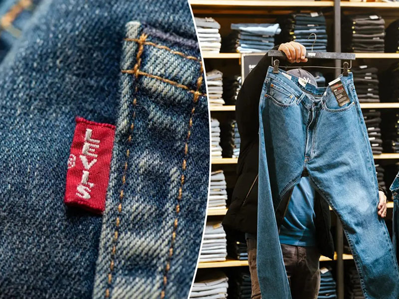 Close-up of a Levi's red tag on blue denim and a person holding a pair of blue Levi's jeans in a store with shelves of folded jeans in the background.