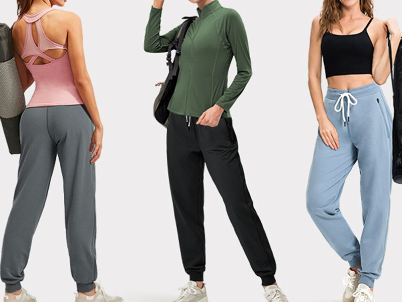 Three women in activewear wearing joggers with pink, black, and blue pants.