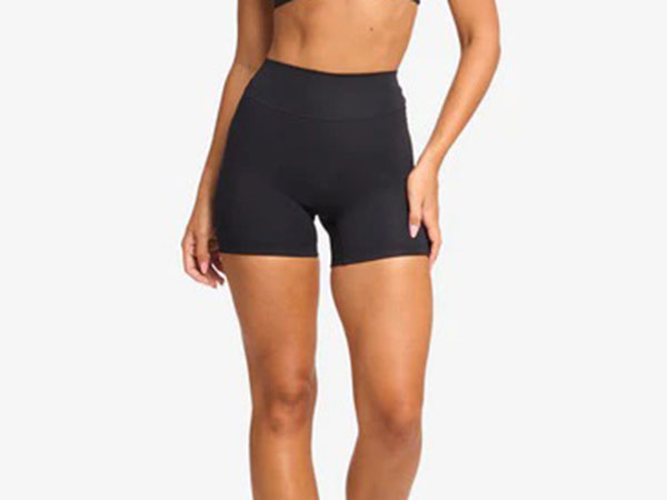 Woman wearing black high-waist fitted shorts, standing with hands relaxed at sides, cropped at midriff and thighs.