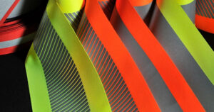 Close-up of reflective ANSI 107 safety tapes in bright neon yellow, green, and orange