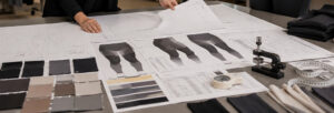 Designers reviewing leggings patterns, fabric swatches, and technical apparel specifications on workspace table during activewear development process