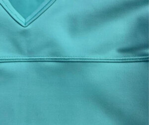 Close-up of turquoise activewear fabric with smooth texture and stitched seam detailing for sports bra or athletic apparel design