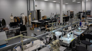 Modern garment manufacturing workshop with sewing machines, pattern tables, mannequins, and apparel development workstations for clothing production and sampling.
