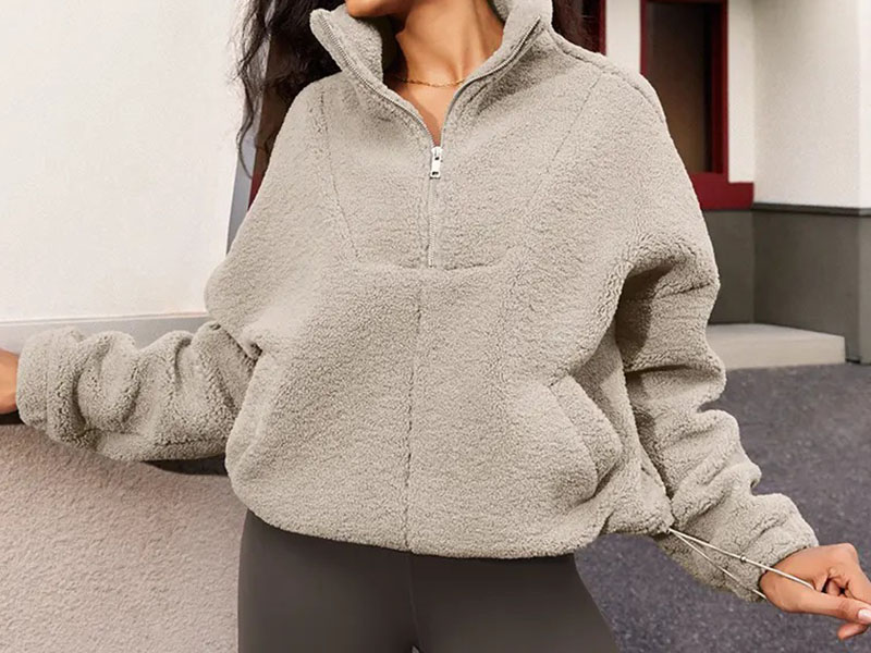 Woman wearing cozy beige fleece jacket with half-zip and adjustable hem, styled casually outdoors