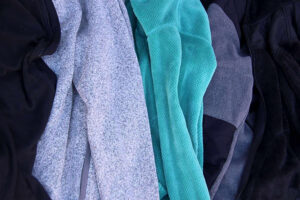 Close-up of various fleece jackets in black, gray, and turquoise, showing soft textures and cozy winter layering fabrics