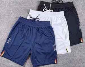 Three pairs of athletic shorts in navy, white, and black with drawstrings and small side accents