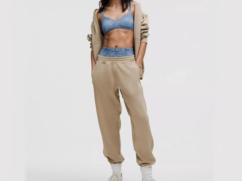 Woman wearing beige jogger sweatpants with matching hoodie, showcasing relaxed fit, soft fabric, and modern athleisure styling for everyday comfort.