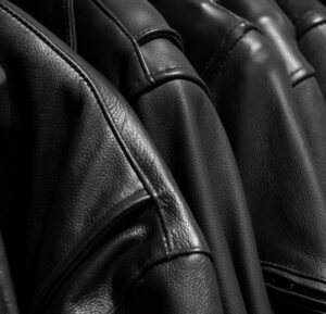 Close-up of black leather jackets showing smooth texture, stitched seams, and premium material finish for fashion outerwear collection.