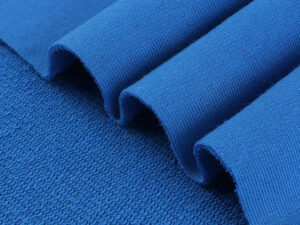 Close-up view of vibrant blue French terry knit fabric folded on itself, highlighting soft textured loops on the underside.