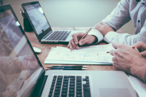 Colleagues reviewing documents and notes beside laptops during office business meeting