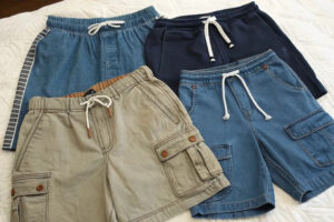 Assorted men’s casual cargo and denim shorts with drawstring waistbands displayed together in different colors and styles.