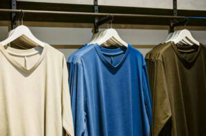 Three solid-color V-neck T-shirts in navy, beige, and green displayed flat on a neutral background.