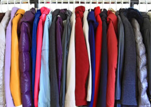 A row of winter jackets in various colors hanging on a clothing rack.