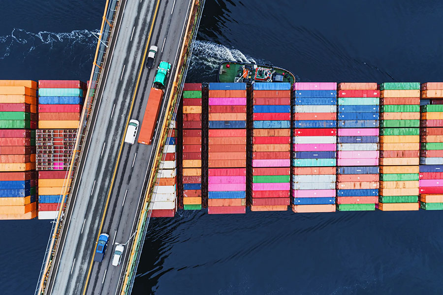 Aerial view of container ship and bridge over stacked containers