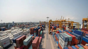 Large container shipping terminal with stacked cargo containers, cranes, and transportation infrastructure, illustrating global trade, import-export operations, and international supply chain logistics.