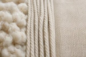 Close-up image showing raw cotton fibers, spun threads, and woven cotton fabric.
