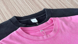 Close-up of black and pink cotton T-shirt necklines on wooden surface.