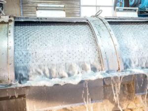Industrial denim washing machine rinsing fabric during garment finishing and textile processing operations.