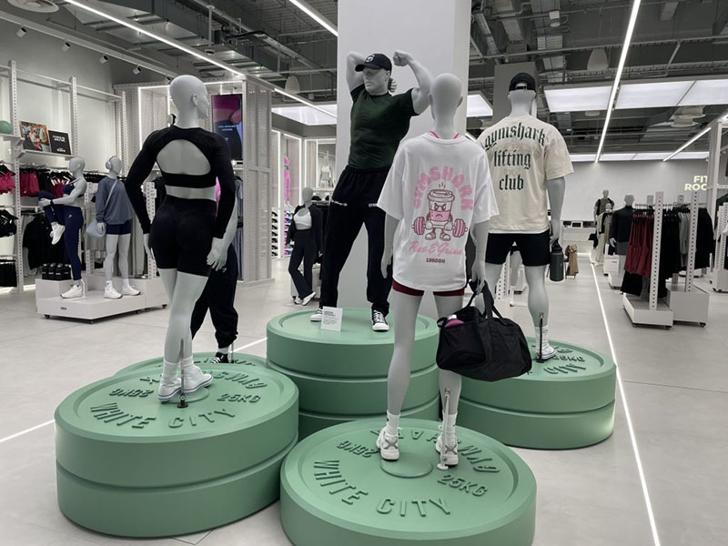 Mannequins showcasing fitness apparel and gym wear collection inside a modern sportswear retail store with athletic clothing displays.