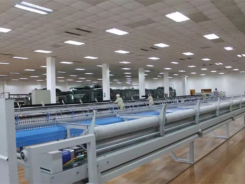 Large textile factory with workers handling fabric on machinery