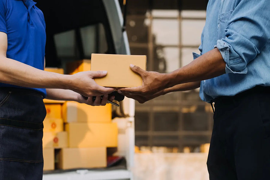 Two workers exchanging package representing Ex Works delivery handover process.