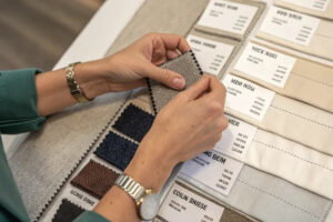 Hands comparing fabric swatches and textile samples for garment design, material selection, and apparel production planning.