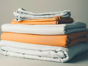 Neatly folded white and orange fabric pieces stacked on table with soft textile texture visible.