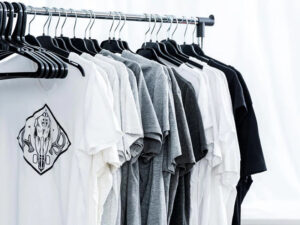 Row of white, gray, and black graphic T-shirts neatly hung on black hangers on a clothing rack.