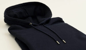 Folded heavyweight black hoodie with drawstring hood, showcasing premium cotton fabric, durable construction, and minimalist streetwear design.