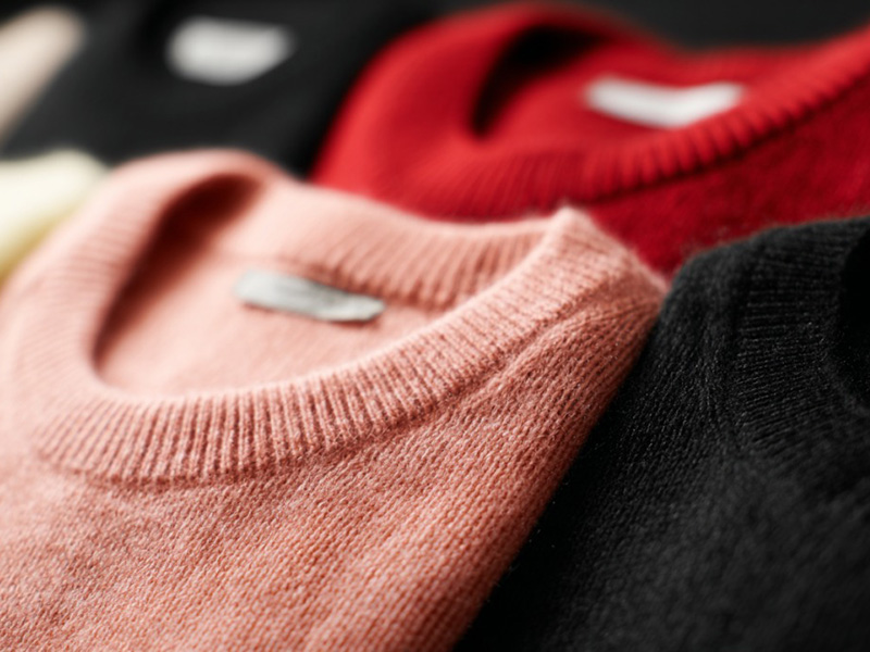 Soft cashmere sweaters in pink, red, and black colors, showcasing fine knit texture, premium fabric quality, and comfortable luxury apparel styling.