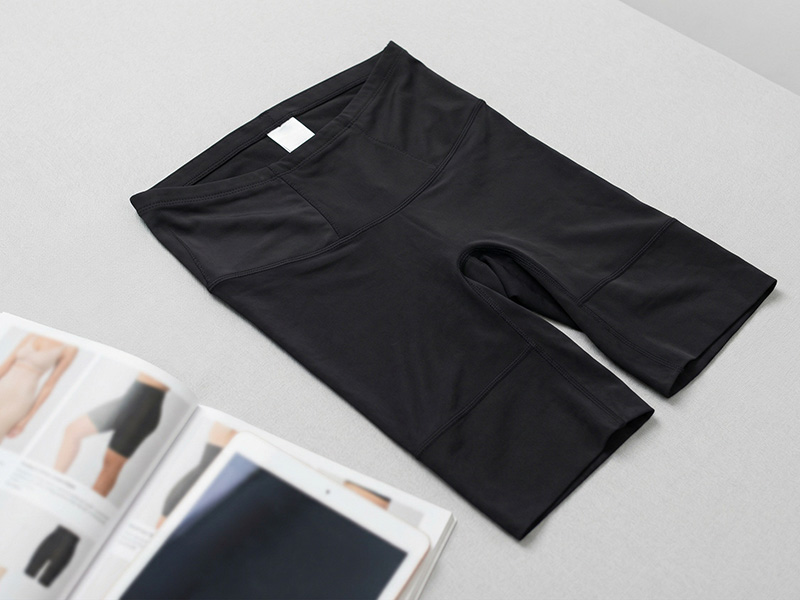 Flat lay of black high-waisted activewear shorts next to a tablet and magazine, showing stretchy workout apparel.
