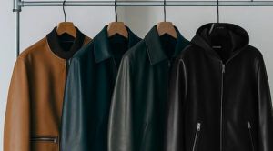Stylish leather jackets hanging on rack in brown, green, and black tones