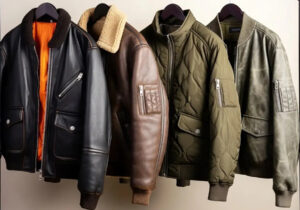 Four bomber jackets in leather and quilted materials hanging on hangers, showcasing different colors and textures.