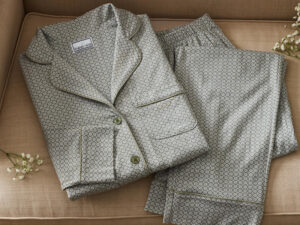 Folded patterned pajama shirt and pants set with contrast piping, featuring a classic button-front design for comfortable sleepwear and lounging.