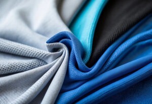 Close-up of breathable performance mesh fabric in blue, black, and gray colors, showcasing lightweight texture for activewear, sportswear, and athletic apparel.