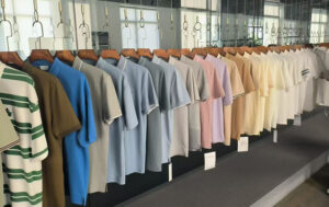 Assorted solid-color and striped T-shirts displayed on hangers in a showroom, showcasing casual apparel styles, color variety, and retail presentation.