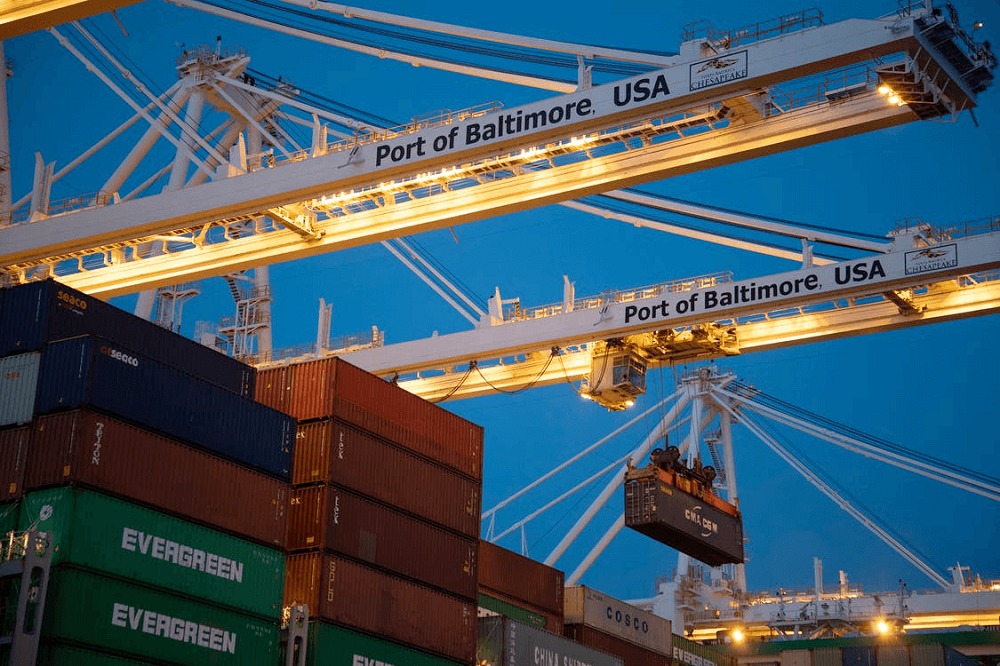 Cargo containers loaded at Baltimore port by cranes at dusk
