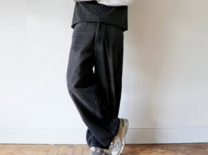 Person wearing dark relaxed-fit wide-leg trousers with casual modern streetwear styling and comfortable loose silhouette indoors