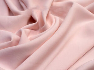 Close-up of soft pink bamboo rayon fabric with smooth texture and gentle folds.