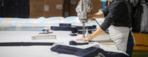Worker cutting fabric using electric fabric cutting machine in a garment factory.