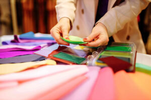 Designer reviewing colorful fabric swatches for textile quality control, evaluating materials, colors, and finishes for apparel production.