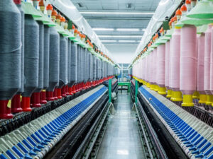 Large textile manufacturing machine with rows of colorful yarn spools in modern fabric production facility.